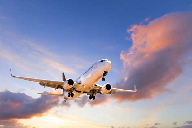 Airplane coming down to land at sunset