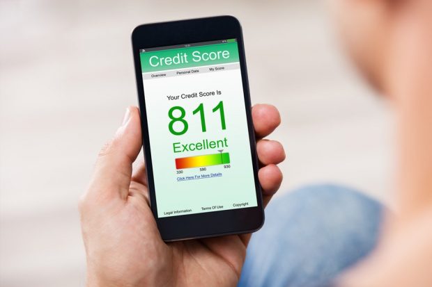 A photograph of a persons hand holding a phone, the phone screen shows their credit score, which is 811 and describes it as 'excellent'
