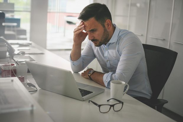 Stressed worker looking at laptop