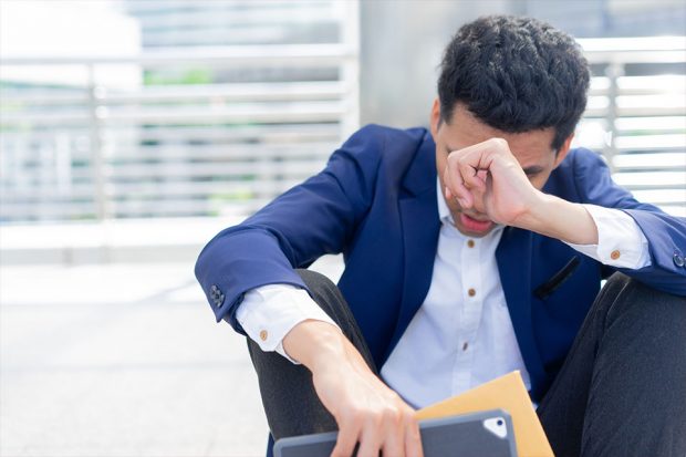 Man in suit, sat outside looking distressed